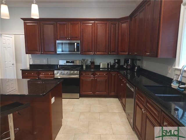 kitchen featuring appliances with stainless steel finishes, dark stone counters, crown molding, sink, and hanging light fixtures