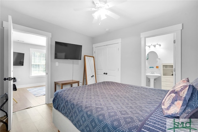 bedroom with ensuite bathroom, light wood-type flooring, sink, a closet, and ceiling fan