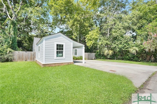 bungalow-style home featuring concrete driveway, a carport, an outdoor structure, and view of scattered trees