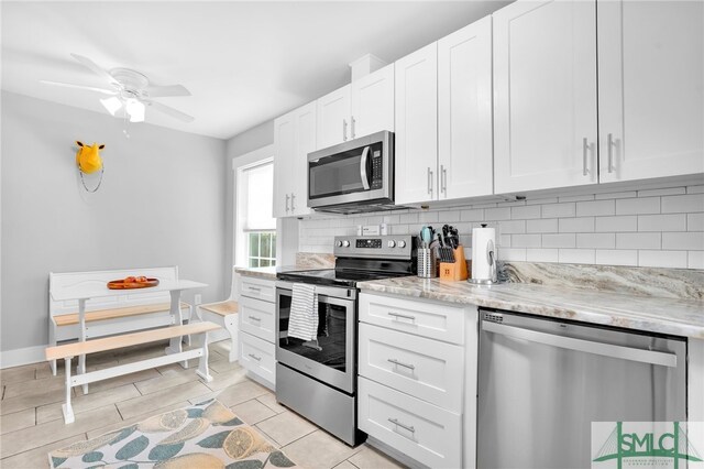 kitchen featuring appliances with stainless steel finishes, tasteful backsplash, white cabinetry, ceiling fan, and light stone counters