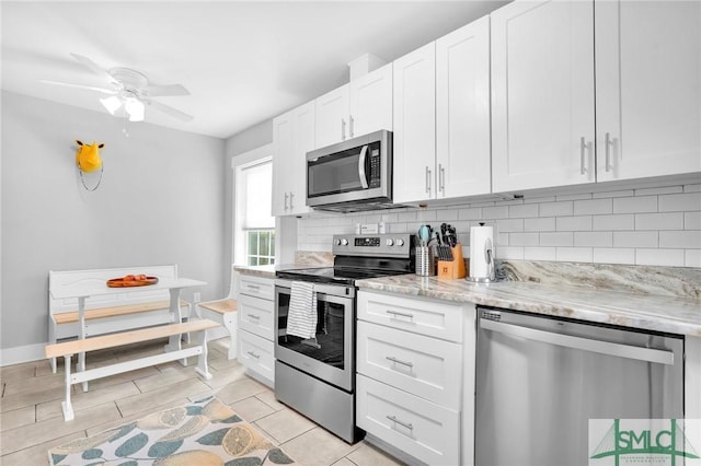 kitchen featuring appliances with stainless steel finishes, backsplash, white cabinets, light stone counters, and ceiling fan