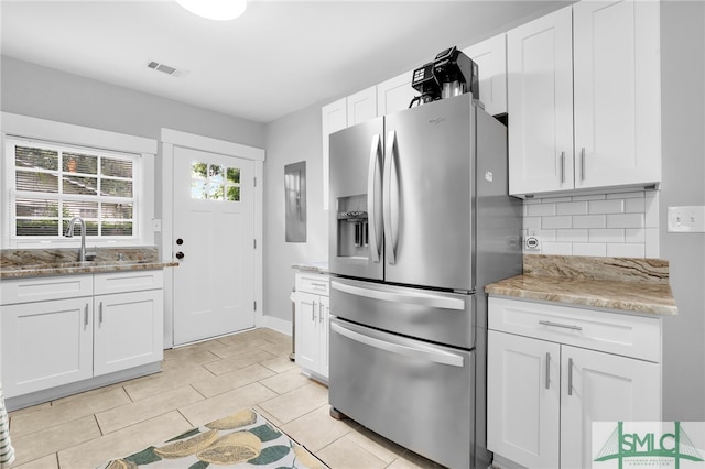 kitchen featuring stainless steel refrigerator with ice dispenser, tasteful backsplash, light stone counters, white cabinets, and light tile patterned flooring