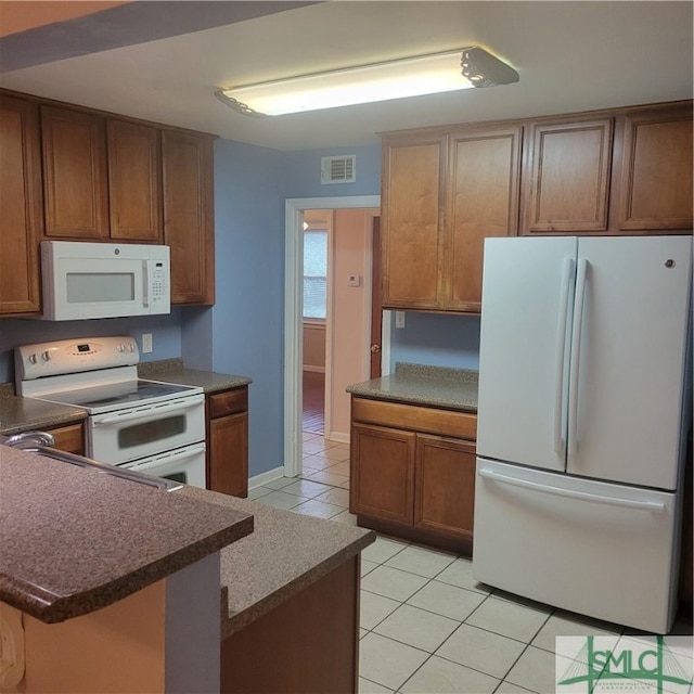 kitchen with white appliances, kitchen peninsula, and light tile patterned flooring