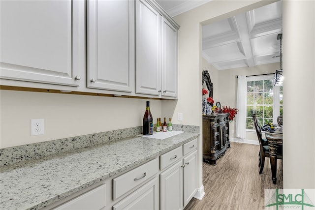 kitchen featuring coffered ceiling, white cabinetry, light stone counters, light wood-type flooring, and beam ceiling