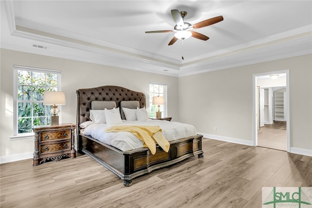 bedroom with ceiling fan, a raised ceiling, hardwood / wood-style flooring, and crown molding