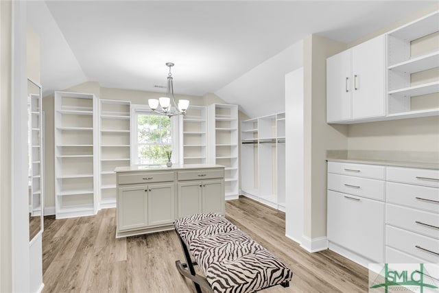 spacious closet featuring lofted ceiling, a chandelier, and light hardwood / wood-style flooring