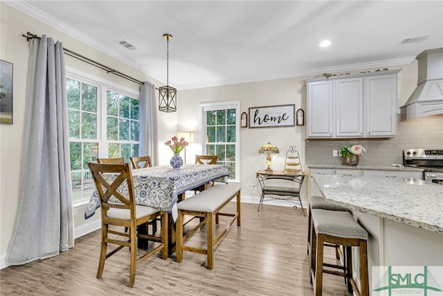 dining area with light hardwood / wood-style flooring and ornamental molding