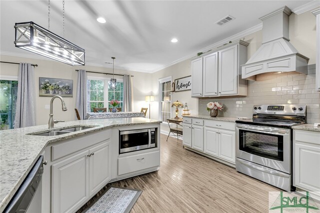 kitchen featuring pendant lighting, custom exhaust hood, sink, white cabinetry, and appliances with stainless steel finishes