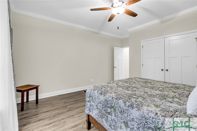 bedroom with ceiling fan, a closet, crown molding, and hardwood / wood-style floors