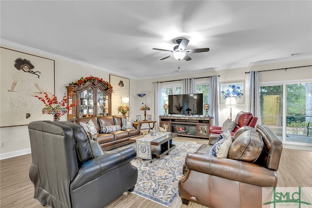 living room featuring ceiling fan, a fireplace, ornamental molding, and a healthy amount of sunlight