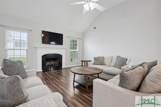 living room featuring a tiled fireplace, dark wood-type flooring, high vaulted ceiling, and ceiling fan