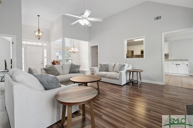 living room featuring dark hardwood / wood-style floors, ceiling fan with notable chandelier, and high vaulted ceiling