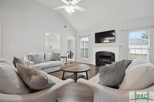 living room featuring high vaulted ceiling, hardwood / wood-style floors, ceiling fan, and a fireplace