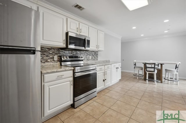 kitchen featuring appliances with stainless steel finishes, light stone counters, white cabinetry, and light tile patterned flooring