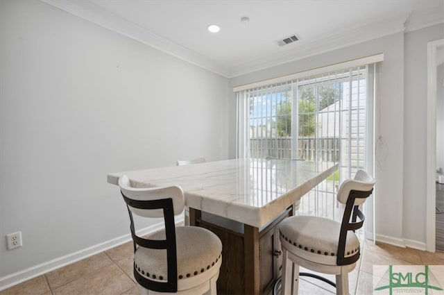 tiled dining area featuring crown molding