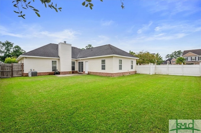 back of property with a yard and central AC