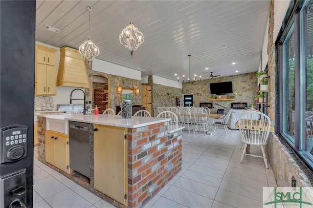 kitchen with plenty of natural light, an inviting chandelier, a kitchen island with sink, and stainless steel dishwasher