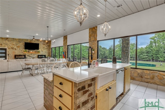 kitchen featuring ceiling fan with notable chandelier, light tile patterned flooring, an island with sink, and sink