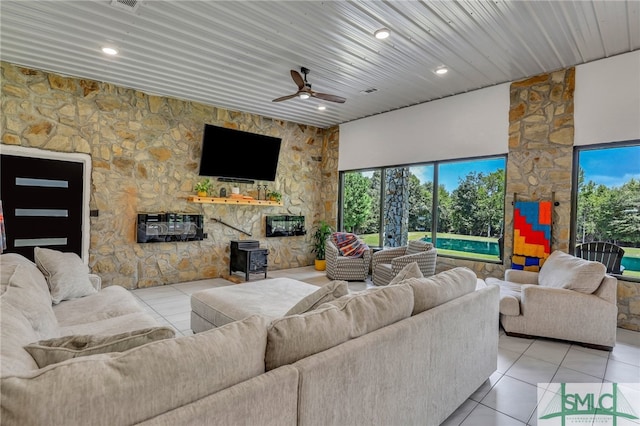 living room featuring a fireplace, a healthy amount of sunlight, light tile patterned floors, and ceiling fan