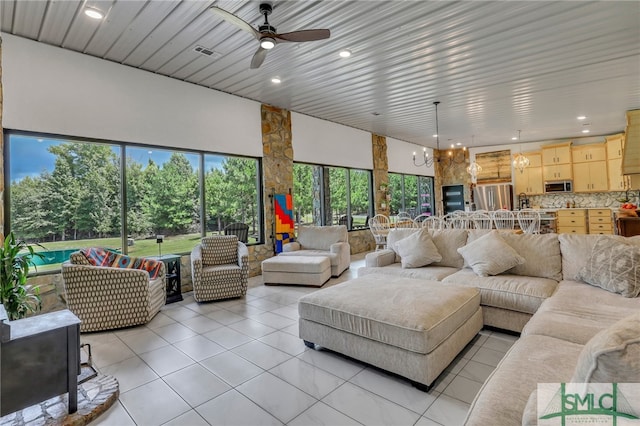 living room with ceiling fan with notable chandelier and light tile patterned floors