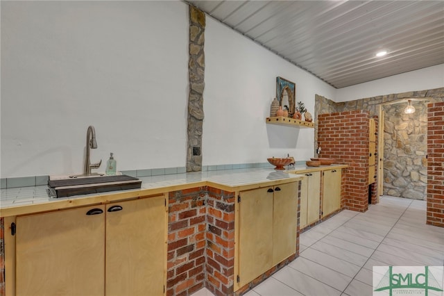 interior space featuring tile counters, kitchen peninsula, sink, and light tile patterned floors