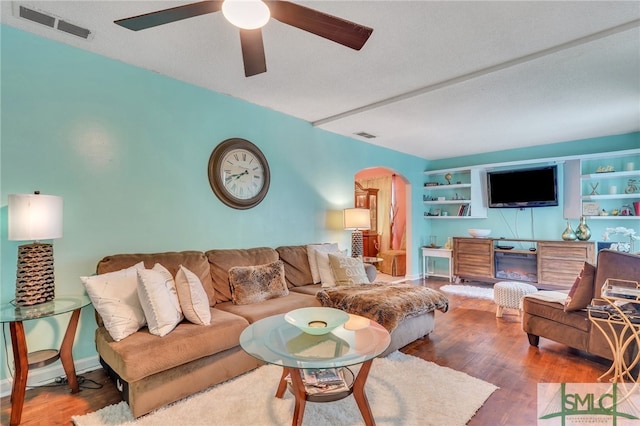 living room featuring a textured ceiling, ceiling fan, and wood-type flooring