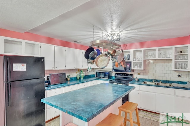 kitchen with a kitchen breakfast bar, black appliances, tasteful backsplash, sink, and white cabinets