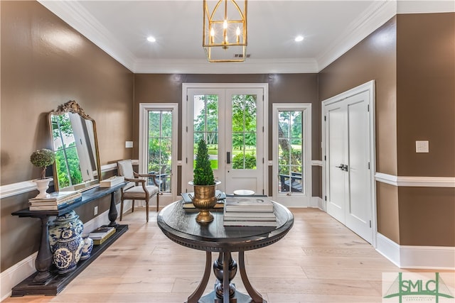 entryway with a notable chandelier, light wood-type flooring, and crown molding