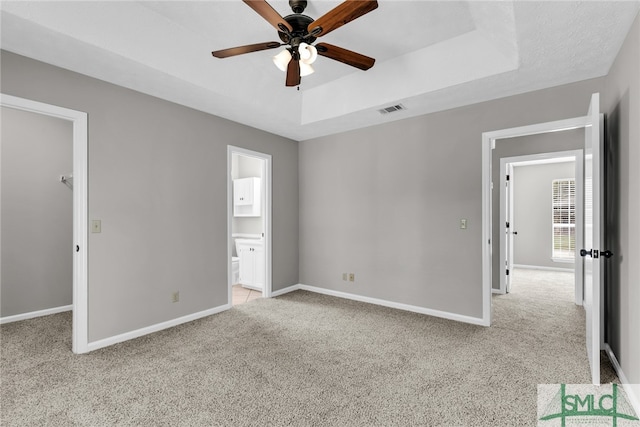 unfurnished bedroom with light colored carpet, ceiling fan, a walk in closet, and a closet