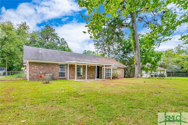 view of front of home with a patio, brick siding, a front yard, and fence