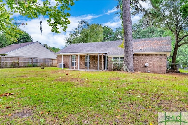 rear view of property featuring cooling unit, a lawn, brick siding, and a fenced backyard