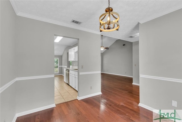 unfurnished dining area featuring wood finished floors, baseboards, visible vents, a textured ceiling, and ceiling fan with notable chandelier