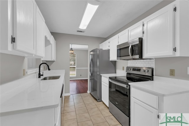 kitchen with white cabinetry, light tile patterned flooring, stainless steel appliances, and sink