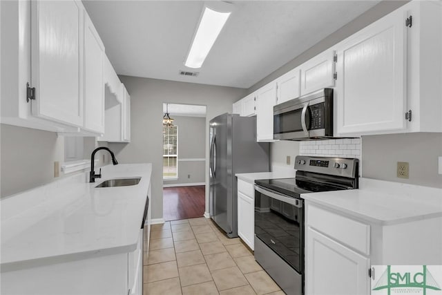 kitchen featuring visible vents, backsplash, stainless steel appliances, white cabinetry, and a sink