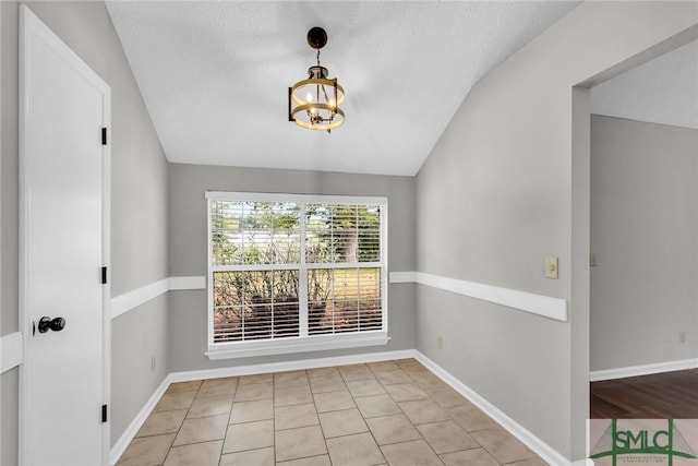 empty room with a chandelier, baseboards, and lofted ceiling