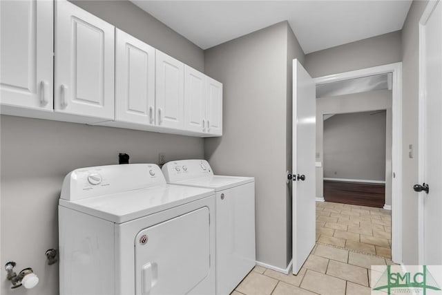 laundry room featuring baseboards, cabinet space, light tile patterned flooring, and washing machine and clothes dryer