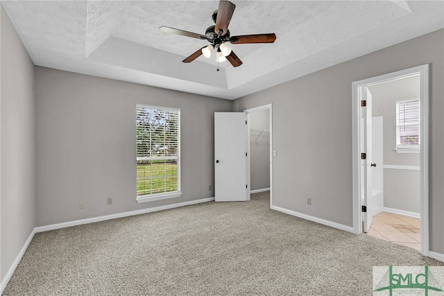 unfurnished room featuring ceiling fan, plenty of natural light, light carpet, and a textured ceiling