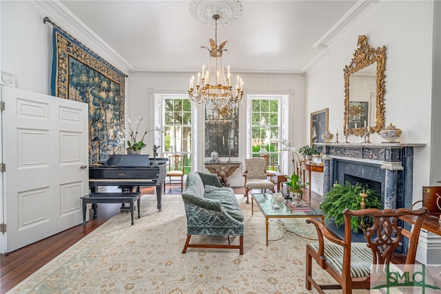 sitting room featuring a fireplace, crown molding, wood-type flooring, and a chandelier