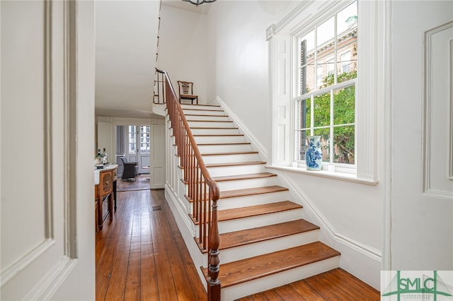 stairs with a healthy amount of sunlight and hardwood / wood-style floors