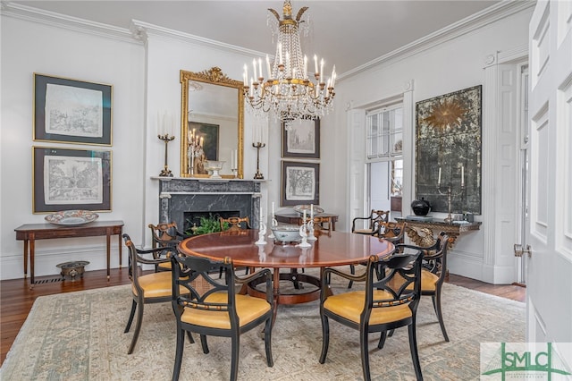 dining space featuring an inviting chandelier, light hardwood / wood-style floors, ornamental molding, and a premium fireplace