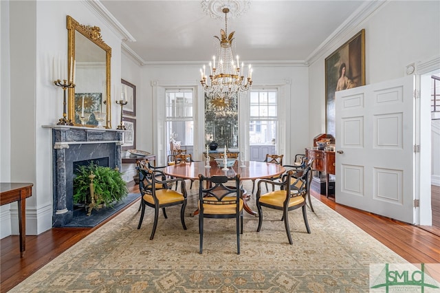 dining area featuring hardwood / wood-style flooring, ornamental molding, a notable chandelier, and a premium fireplace