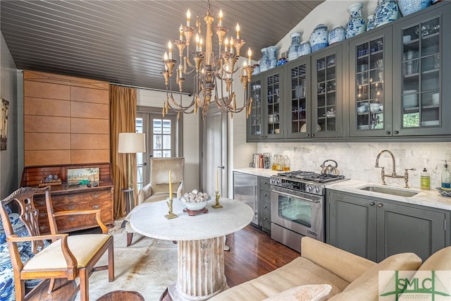 kitchen with high end stainless steel range oven, a notable chandelier, dark hardwood / wood-style floors, and sink