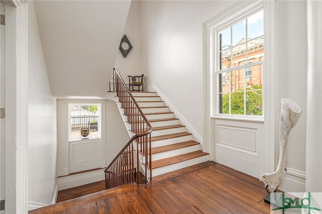 stairway featuring lofted ceiling and wood-type flooring