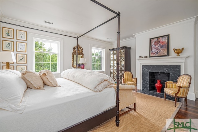 bedroom with crown molding, hardwood / wood-style flooring, and a fireplace