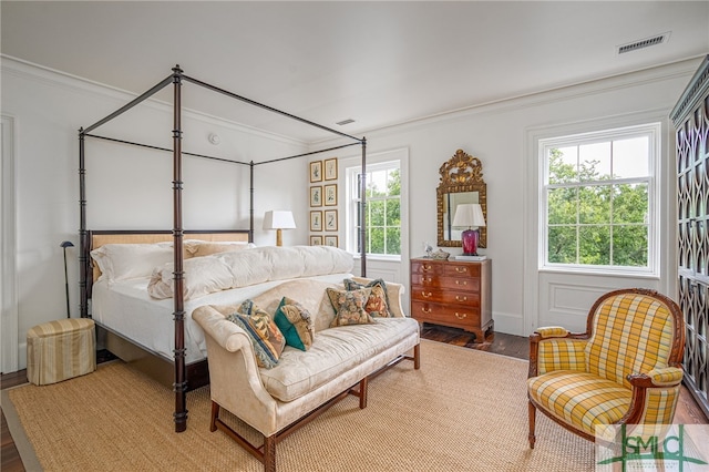 bedroom featuring hardwood / wood-style flooring, ornamental molding, and multiple windows