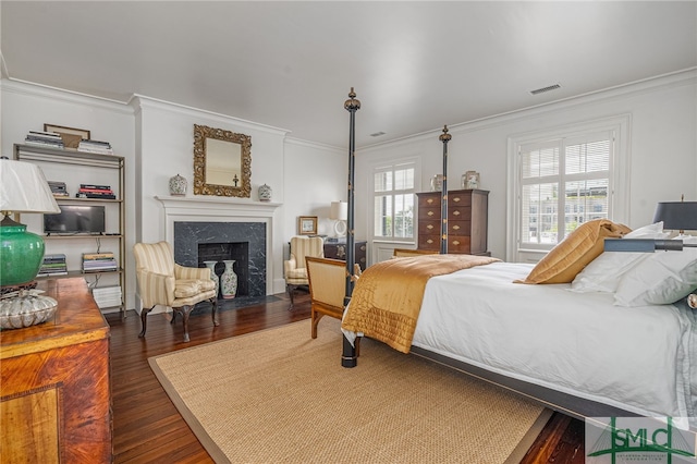 bedroom featuring crown molding, a premium fireplace, and dark hardwood / wood-style floors