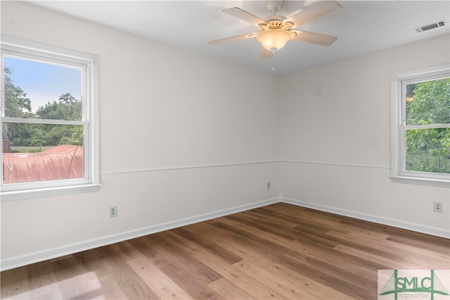 spare room featuring ceiling fan, a wealth of natural light, and dark hardwood / wood-style flooring