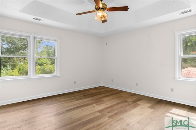 empty room featuring hardwood / wood-style floors, ceiling fan, and a tray ceiling