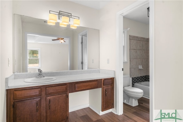 full bathroom with vanity, hardwood / wood-style floors, toilet, ceiling fan, and tiled shower / bath combo