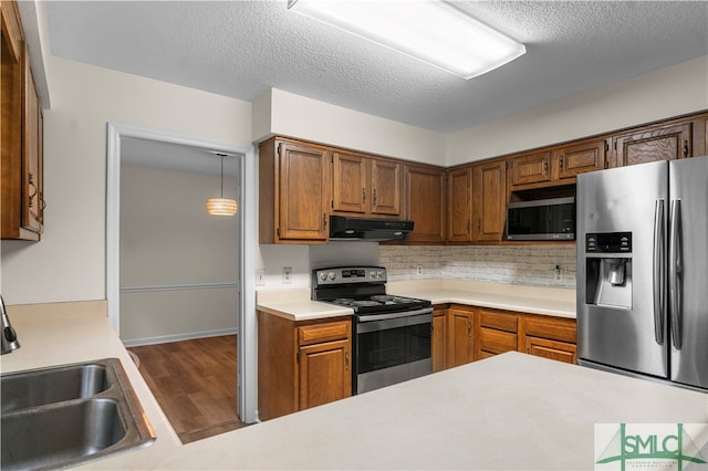 kitchen with a textured ceiling, dark hardwood / wood-style floors, appliances with stainless steel finishes, sink, and ventilation hood